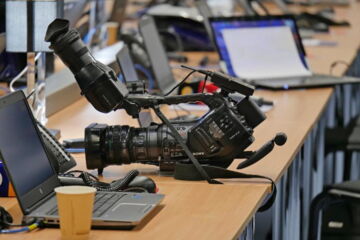 Medienalltag: Eine Kamera und zwei Laptops auf einem Tisch